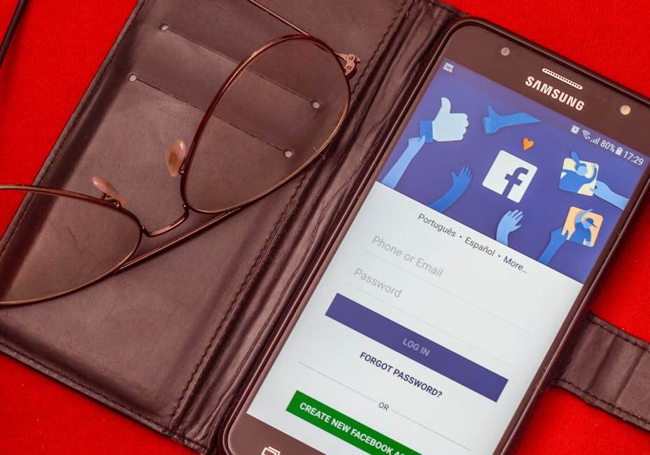 Samsung phone on Facebook login screen with eyeglasses and wallet on red background.